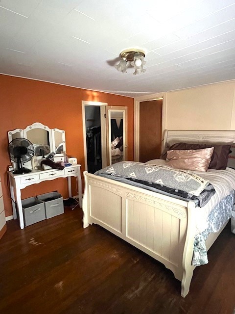 bedroom with a closet, dark hardwood / wood-style flooring, and a walk in closet