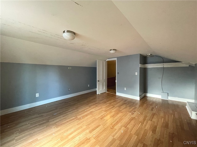 additional living space with wood-type flooring and vaulted ceiling