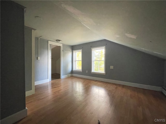 additional living space with hardwood / wood-style floors and vaulted ceiling