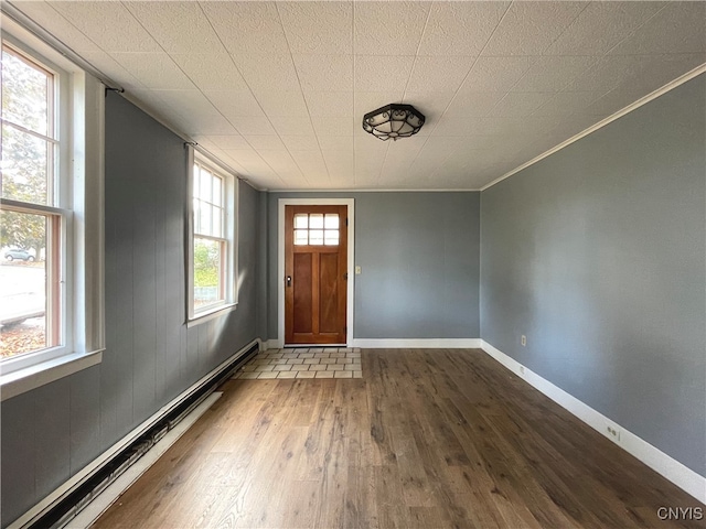 entrance foyer with hardwood / wood-style floors, baseboard heating, and crown molding