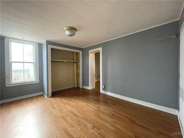 unfurnished bedroom with light hardwood / wood-style flooring, a closet, and ornamental molding