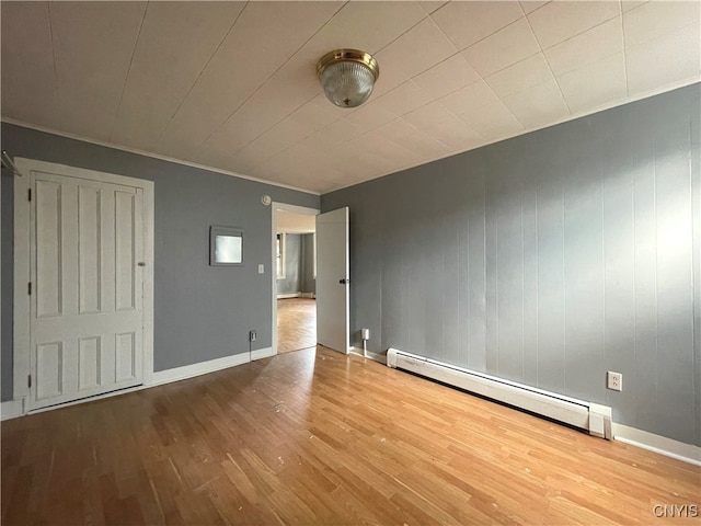 empty room with crown molding, a baseboard radiator, and light hardwood / wood-style floors