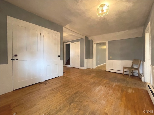 interior space with hardwood / wood-style floors, baseboard heating, and lofted ceiling