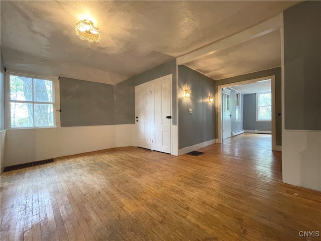 spare room featuring wood-type flooring and a baseboard radiator