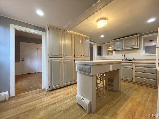 kitchen with a kitchen bar, a center island, light hardwood / wood-style flooring, and sink