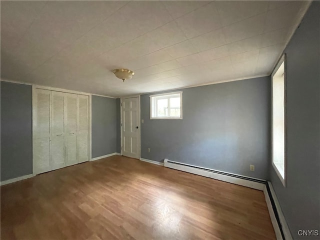 unfurnished bedroom with hardwood / wood-style floors and a baseboard radiator