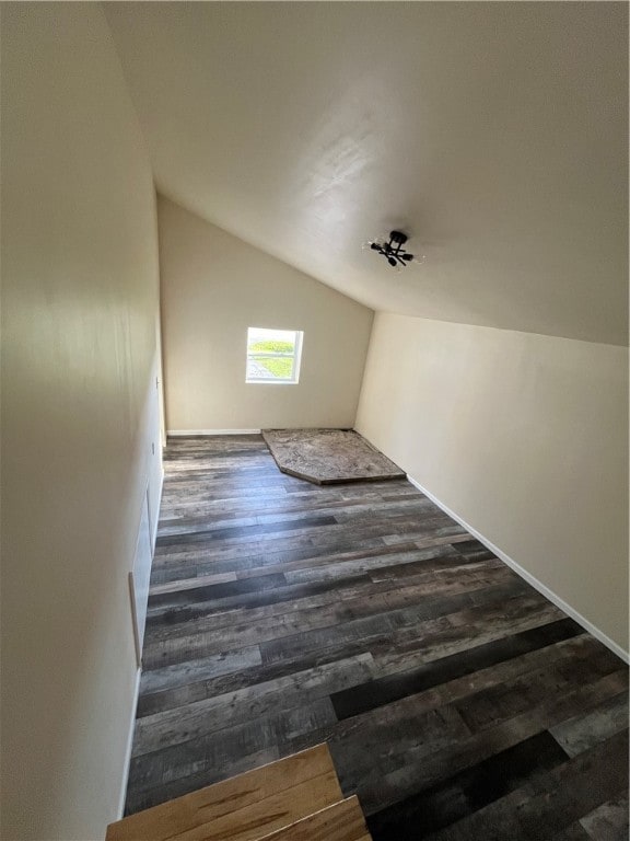 additional living space featuring dark wood-type flooring and vaulted ceiling