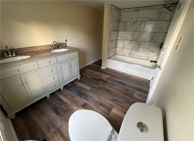 bathroom featuring a tile shower, hardwood / wood-style flooring, vanity, and toilet