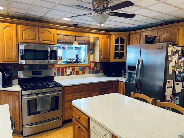 kitchen with ceiling fan, pendant lighting, light hardwood / wood-style flooring, stainless steel appliances, and decorative backsplash