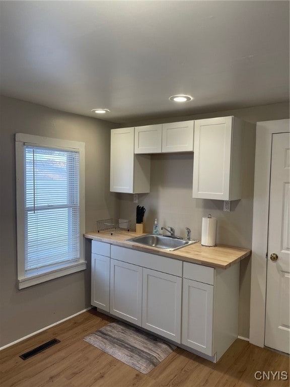 kitchen featuring light wood-type flooring, white cabinetry, and sink