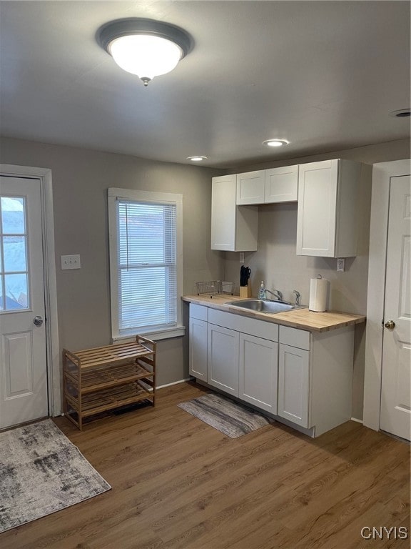 kitchen with wood-type flooring, sink, and white cabinetry