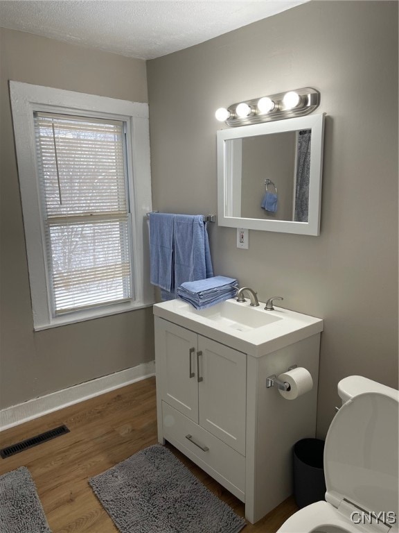 bathroom featuring a healthy amount of sunlight, hardwood / wood-style floors, and toilet