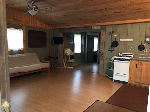 kitchen with lofted ceiling, light wood-type flooring, wood ceiling, white stove, and wood walls