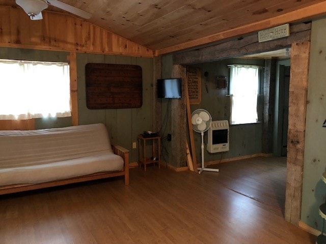 unfurnished room with ceiling fan, hardwood / wood-style floors, wooden ceiling, heating unit, and vaulted ceiling