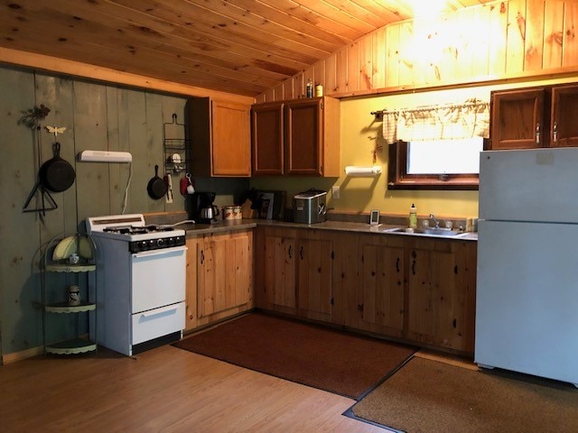 kitchen with sink, white appliances, wooden ceiling, light wood-type flooring, and vaulted ceiling