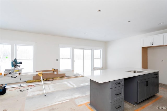 kitchen with an island with sink, gray cabinets, and light countertops