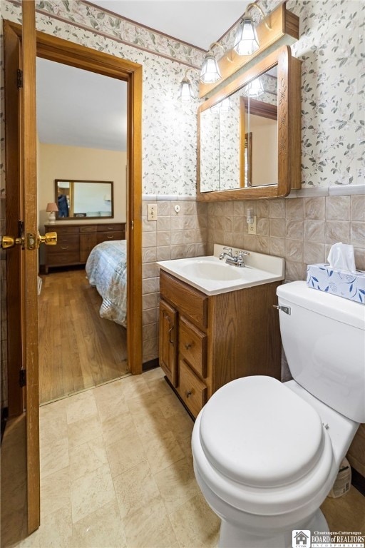 bathroom with vanity, tile walls, and toilet