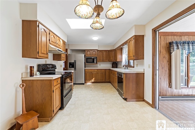 kitchen with a skylight, black appliances, decorative light fixtures, and sink