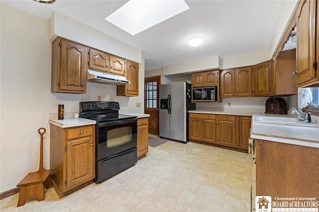 kitchen featuring a skylight, black appliances, and sink