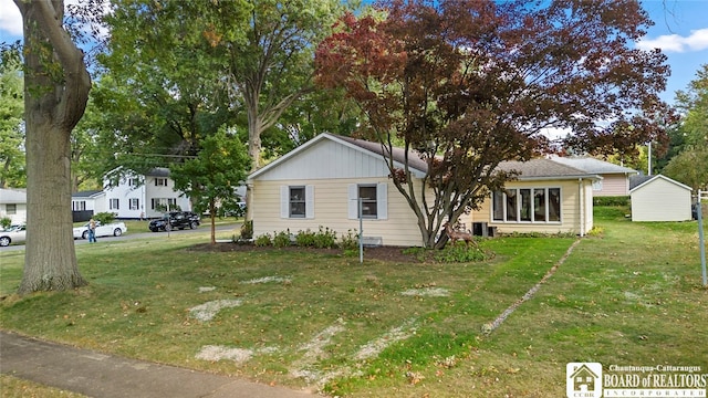 view of front of property featuring a front lawn and a shed