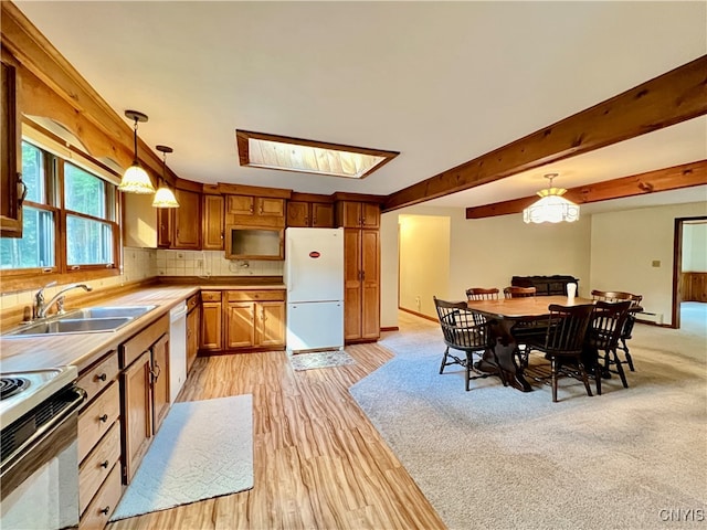 kitchen with pendant lighting, a skylight, sink, white appliances, and backsplash