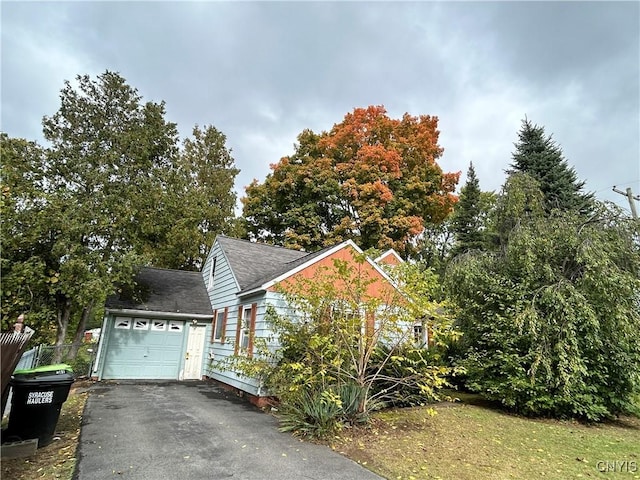view of property exterior with an attached garage, a shingled roof, aphalt driveway, and fence