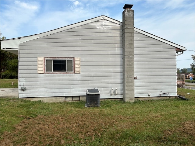 view of side of property featuring a yard and central AC