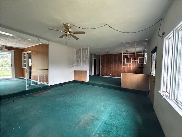 unfurnished room featuring ceiling fan, a textured ceiling, and wood walls