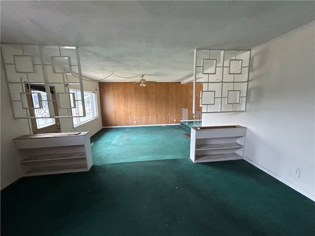 interior space with ceiling fan, wood walls, and a textured ceiling