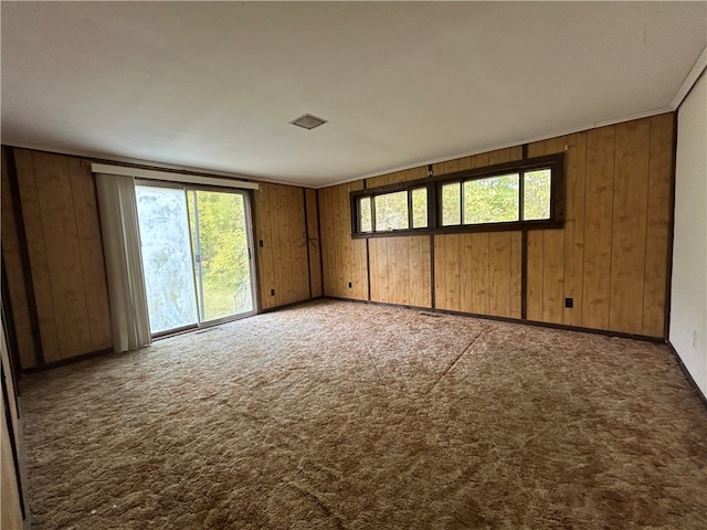 carpeted spare room with wooden walls