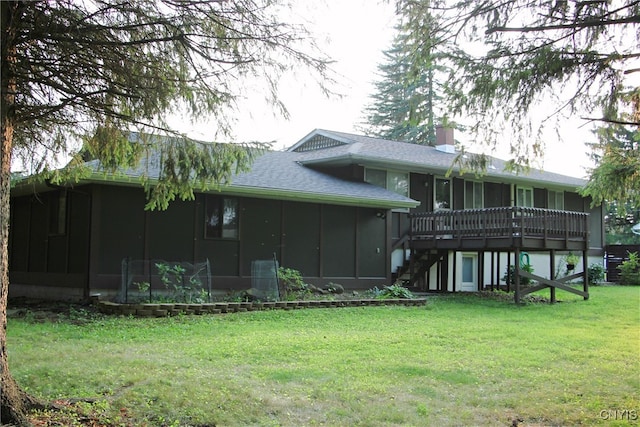 rear view of property featuring a sunroom, a lawn, and a deck