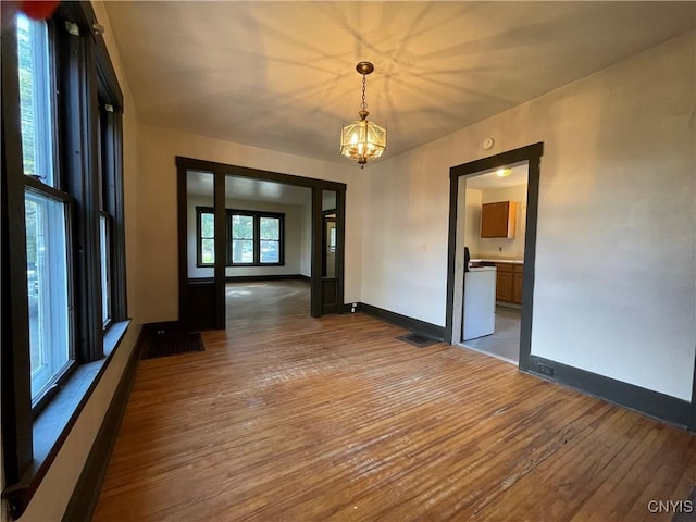 unfurnished room featuring wood-type flooring and an inviting chandelier