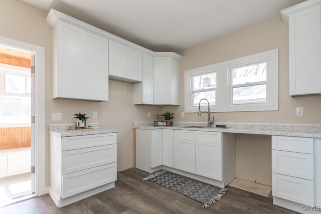 kitchen with light stone counters, white cabinets, sink, and dark hardwood / wood-style flooring