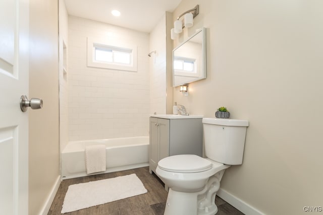 full bathroom featuring wood-type flooring, tiled shower / bath, vanity, and toilet