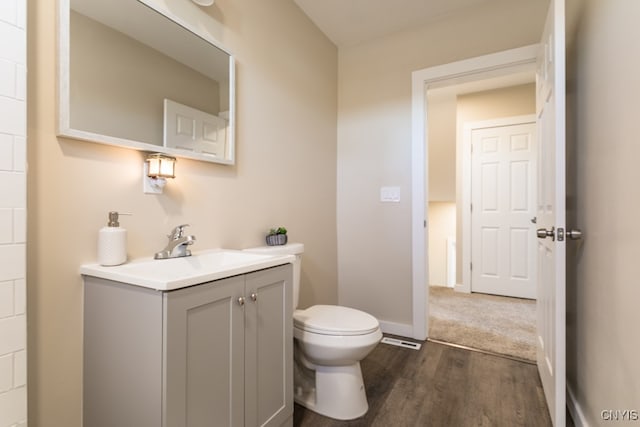 bathroom with wood-type flooring, vanity, and toilet