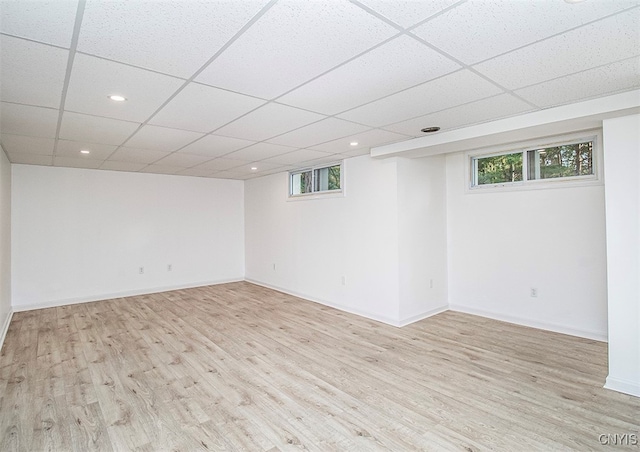 basement with light hardwood / wood-style flooring, plenty of natural light, and a paneled ceiling