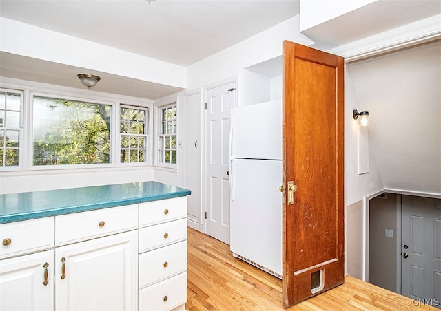 kitchen featuring white refrigerator, light hardwood / wood-style flooring, and white cabinets