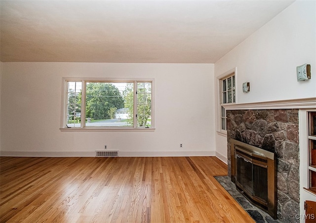 living room with a stone fireplace and light wood-type flooring