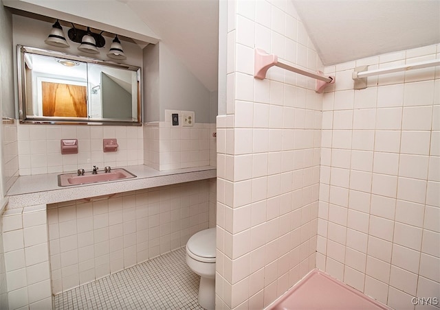 bathroom featuring a shower, tile walls, sink, and toilet