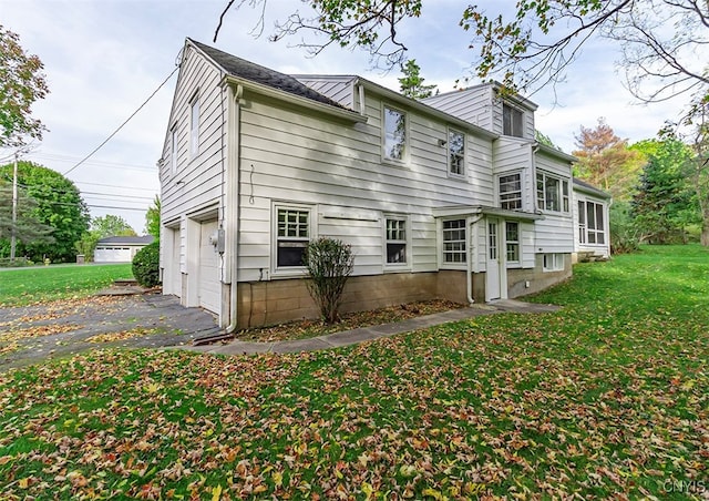 rear view of property featuring a garage and a yard