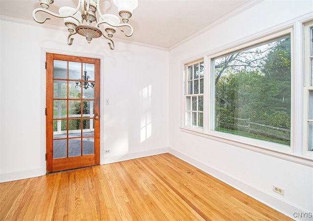 unfurnished dining area featuring light hardwood / wood-style flooring, crown molding, and a chandelier