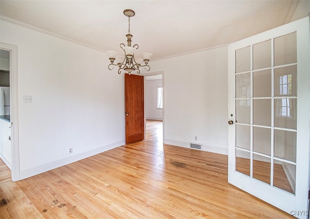 spare room with a notable chandelier, light hardwood / wood-style flooring, and ornamental molding