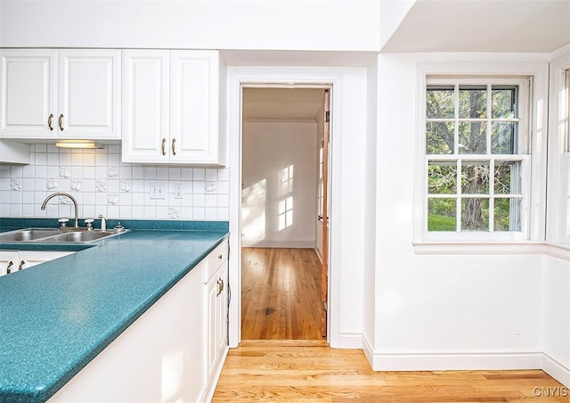 kitchen with light hardwood / wood-style floors, backsplash, sink, and white cabinetry