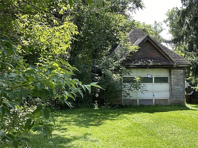 exterior space with a garage, an outbuilding, and a lawn