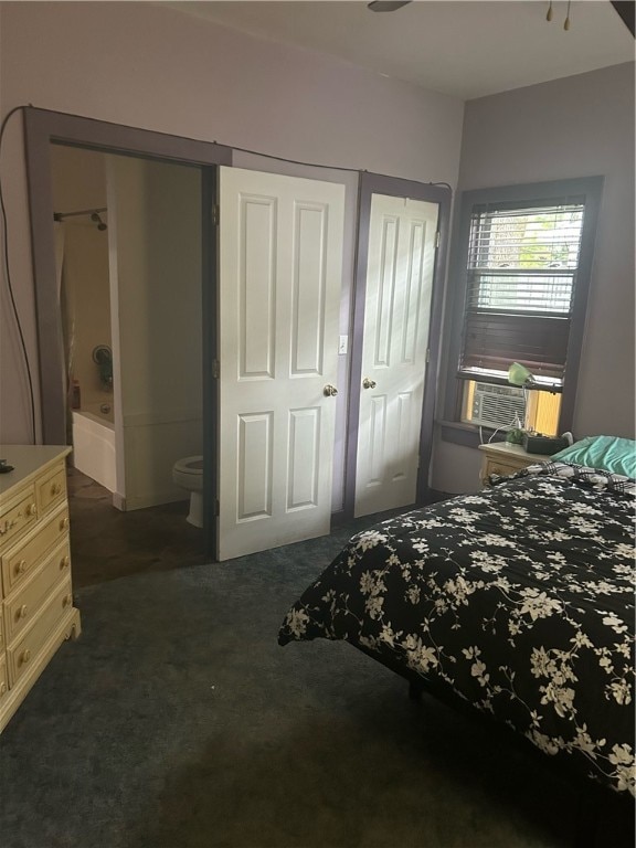 bedroom with dark carpet, cooling unit, and ensuite bath