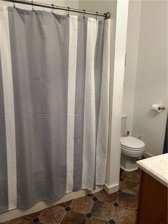 bathroom featuring tile patterned floors, toilet, walk in shower, and vanity