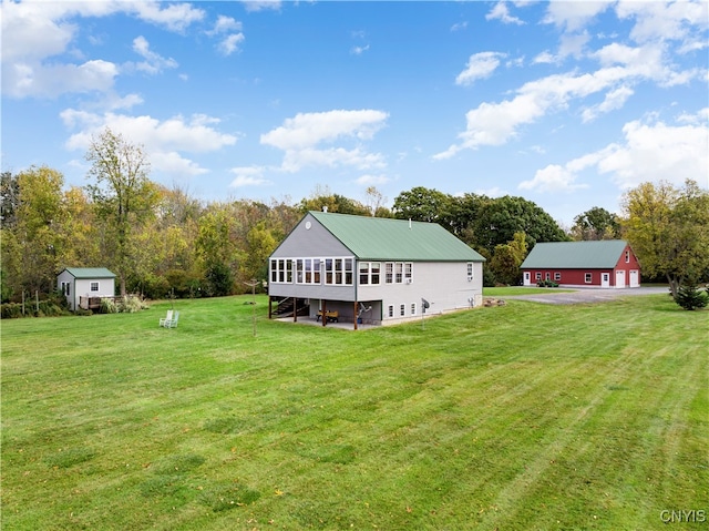 rear view of house featuring an outdoor structure and a yard