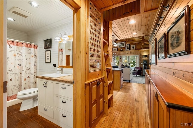 bathroom featuring vanity, wooden walls, toilet, and hardwood / wood-style floors