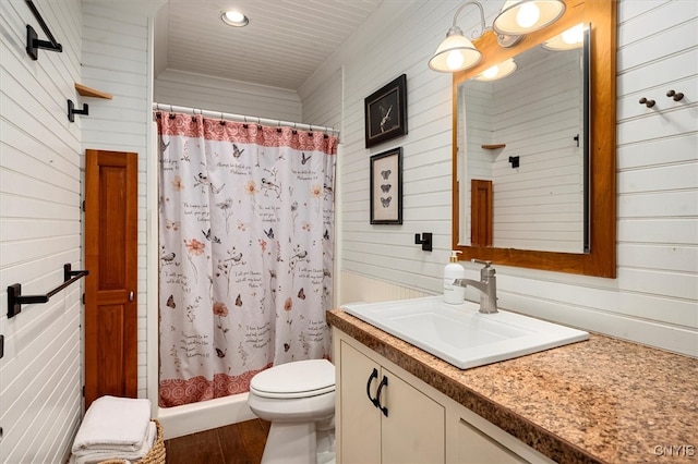 bathroom with vanity, wood walls, hardwood / wood-style floors, curtained shower, and toilet