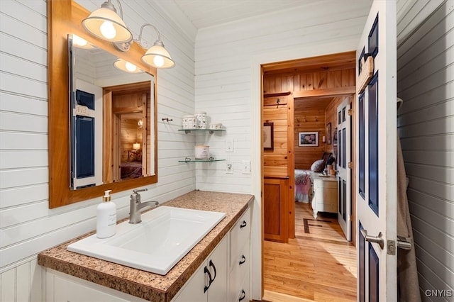 bathroom with wood walls, hardwood / wood-style flooring, and vanity